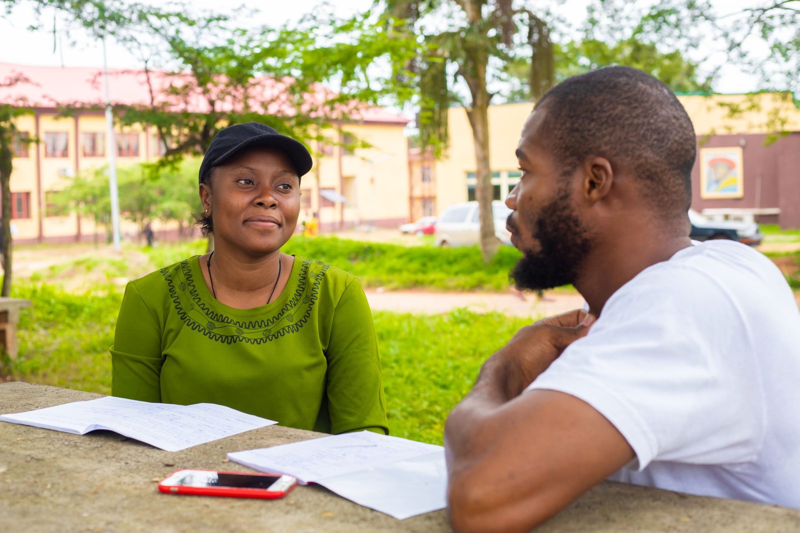 Black university handsome man assisting his female friend with her lecture in the campus. Focus is on student.
